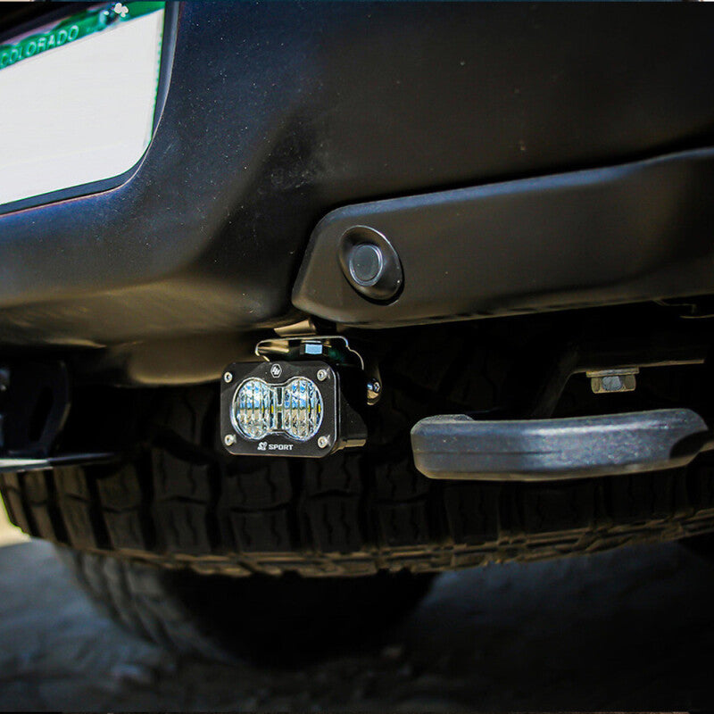 Installed Baja Designs S2 dual reverse LED light on a 2021+ RAM 1500 TRX, mounted under the rear bumper for improved reverse visibility and trail lighting.