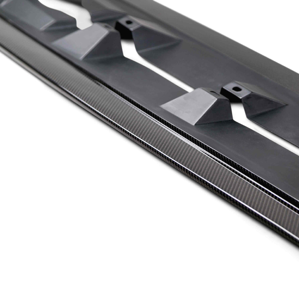 Close-up view highlighting carbon fiber weave texture and fitment against OEM rockers.