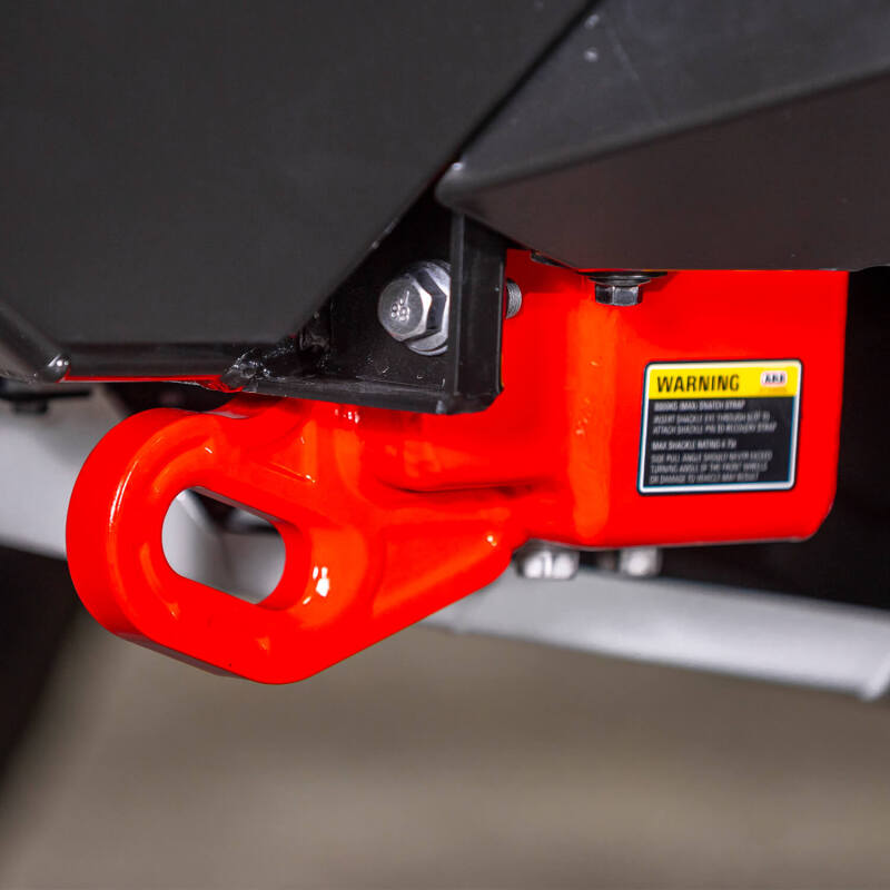Representative installed close up of a red ARB forged recovery point showing the ARB warning label with the 8000 kg maximum snatch strap and 4.75 tonne shackle ratings, pictured with under vehicle protection that is not included