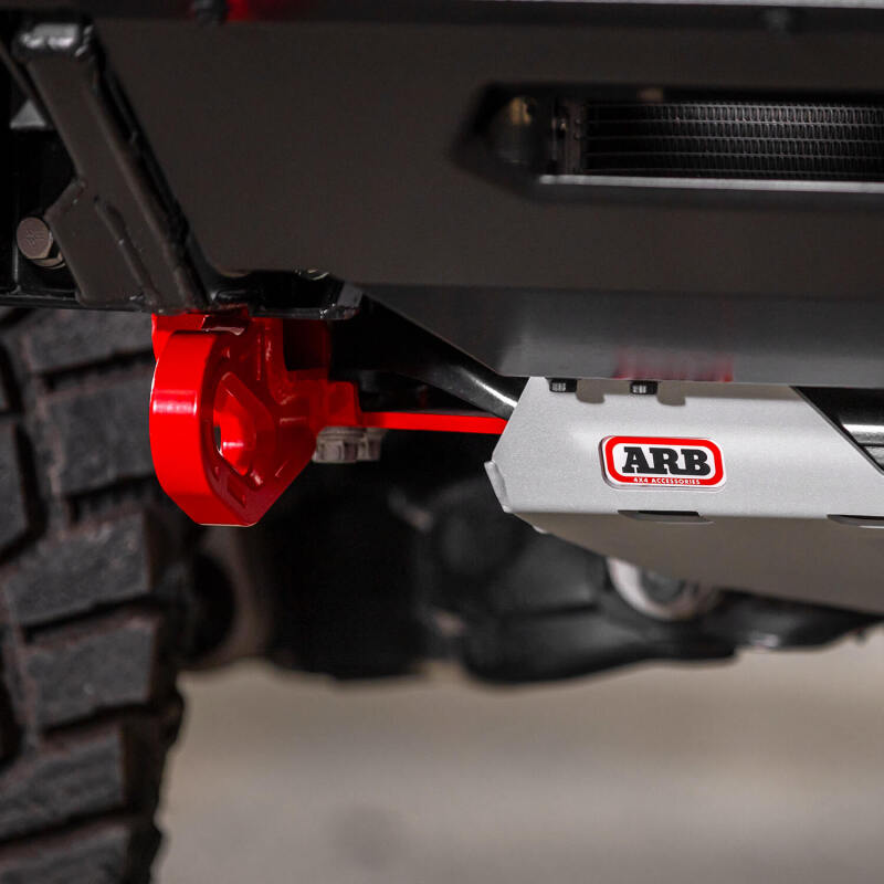 Representative side profile of a red ARB forged recovery point mounted to the chassis rail of a Toyota Land Cruiser 250 beside an ARB skid plate that is not included