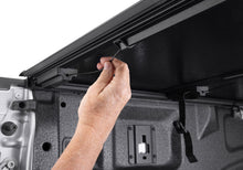 Load image into Gallery viewer, Hand securing the BAKFlip G2 latch strap inside the Ford Ranger 5-foot bed
