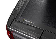 Load image into Gallery viewer, Close-up of the BAKFlip G2 cover corner and RealTruck brand badge, 5-foot bed version