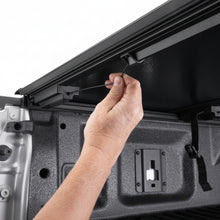 Load image into Gallery viewer, Hand securing the BAKFlip G2 latch strap inside the truck bed