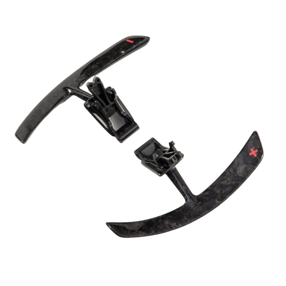 Porsche 991 carbon paddle shifter extensions with the badge on one paddle and the bracket visible on the other