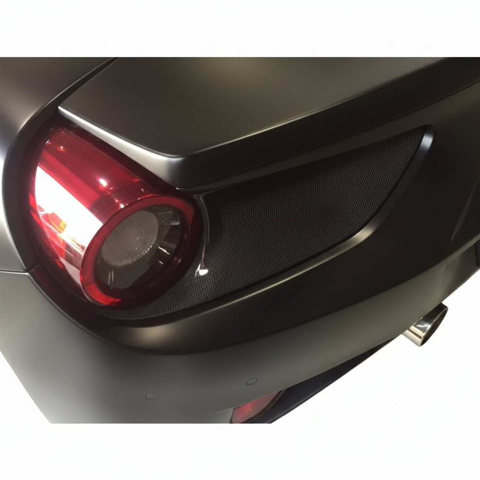 Carbon fiber tail light surround installed around the round red rear light of a matte finished Ferrari 488