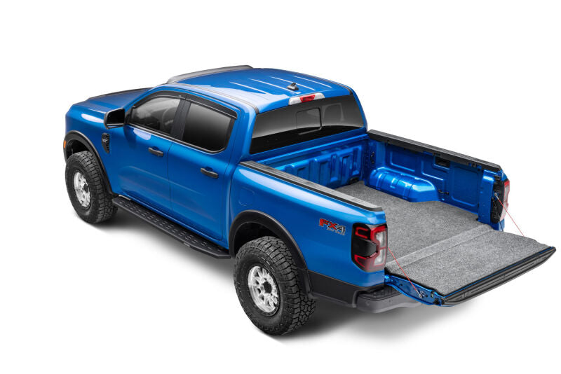 Blue truck with Husky Liners bed liner installed, side rear three-quarter view with tailgate down