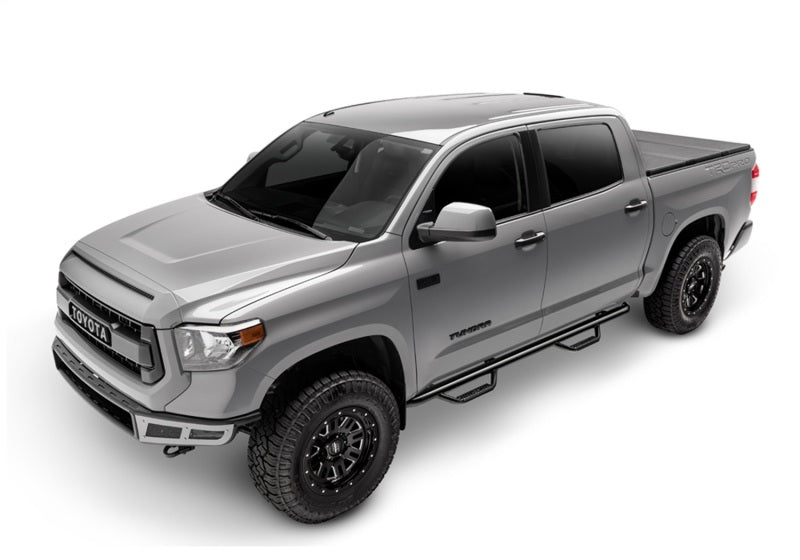 Silver crew cab pickup with N-Fab nerf steps installed, rear three-quarter view