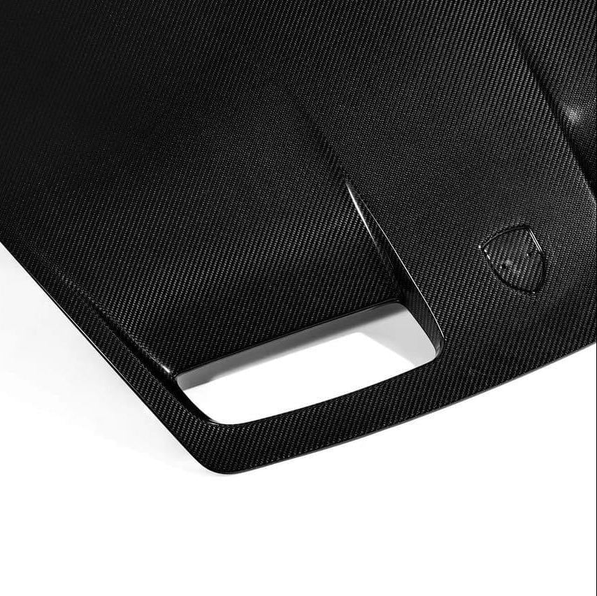 Porsche 992 GT3 carbon fiber hood top view showing the twill weave surface and Porsche crest decal