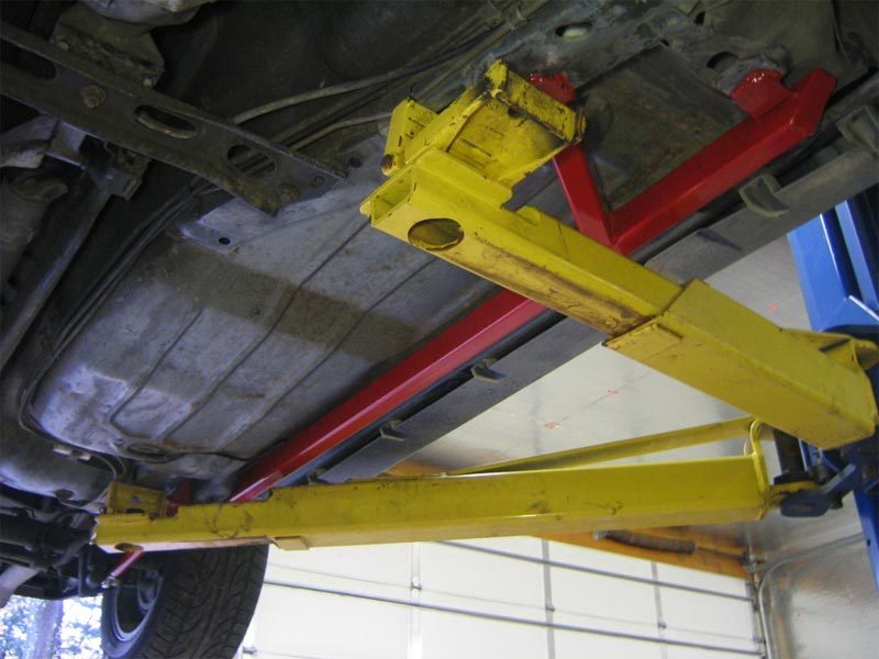 Three piece black UMI 2400-B subframe connector set laid out with the passenger side jog-over piece