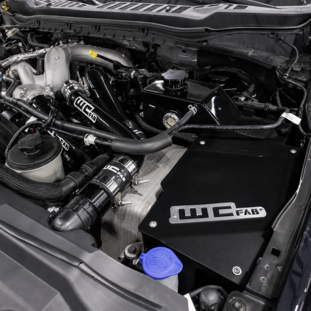 Overhead view of the coolant tank and battery box kit positioned in the engine bay